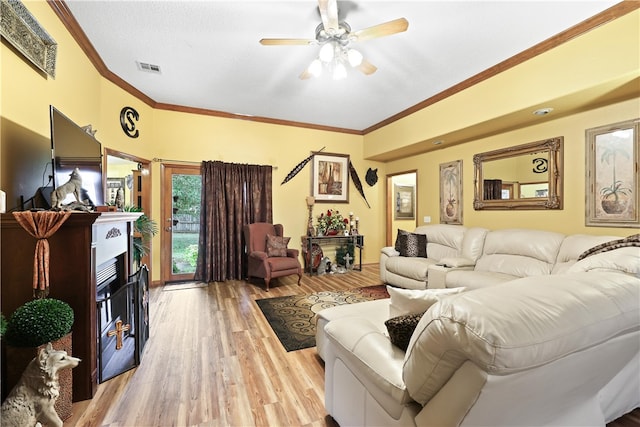 living room featuring ceiling fan, ornamental molding, and light wood-type flooring