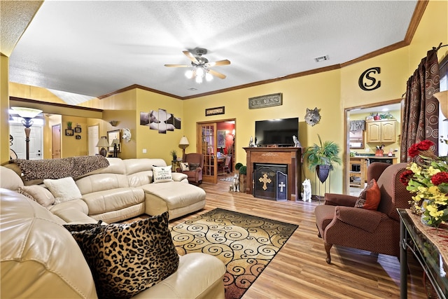 living room with a textured ceiling, light hardwood / wood-style flooring, ceiling fan, and ornamental molding