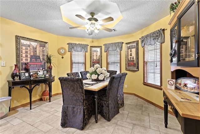 tiled dining room with ceiling fan, plenty of natural light, and a textured ceiling