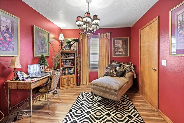 home office featuring an inviting chandelier, a textured ceiling, and light wood-type flooring