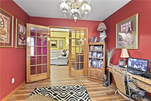 office area featuring french doors, hardwood / wood-style floors, a textured ceiling, and an inviting chandelier