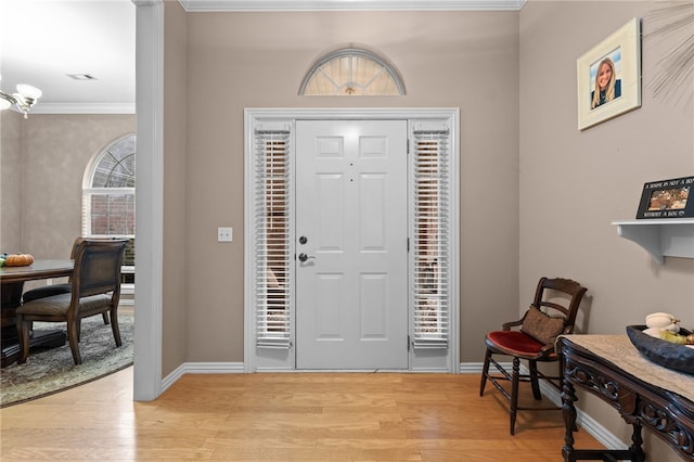 entryway featuring an inviting chandelier, crown molding, and light hardwood / wood-style flooring