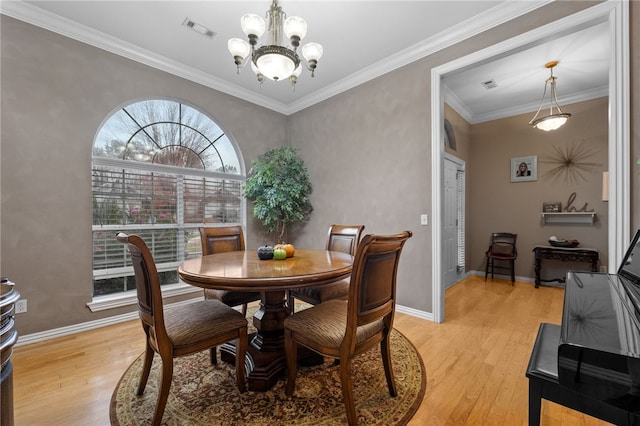 dining room featuring a chandelier, light hardwood / wood-style floors, and crown molding