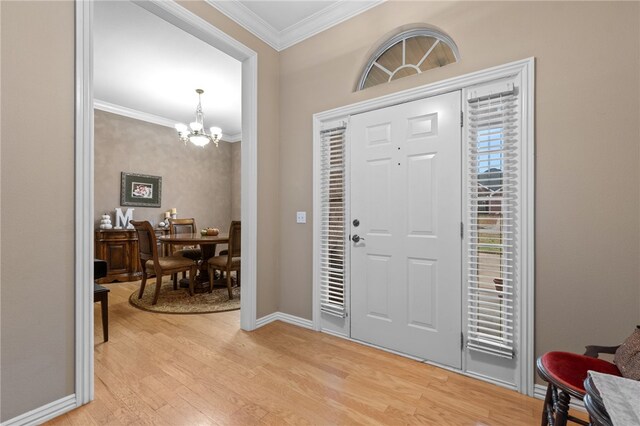 foyer with light wood-type flooring, crown molding, and a notable chandelier