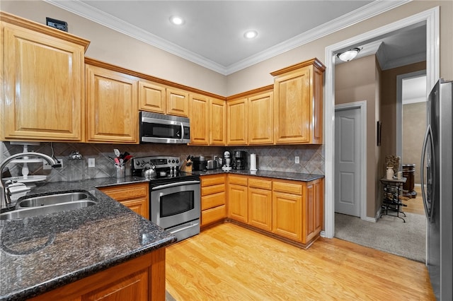 kitchen featuring backsplash, sink, light wood-type flooring, and appliances with stainless steel finishes