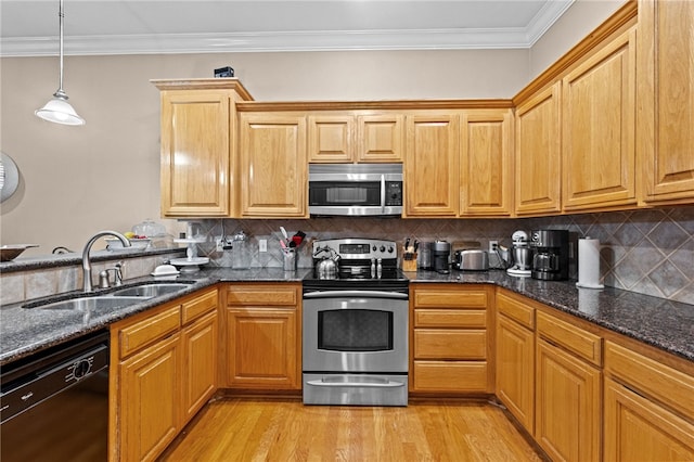 kitchen with appliances with stainless steel finishes, dark stone counters, sink, decorative light fixtures, and light hardwood / wood-style flooring