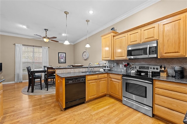 kitchen featuring appliances with stainless steel finishes, light hardwood / wood-style flooring, hanging light fixtures, and sink