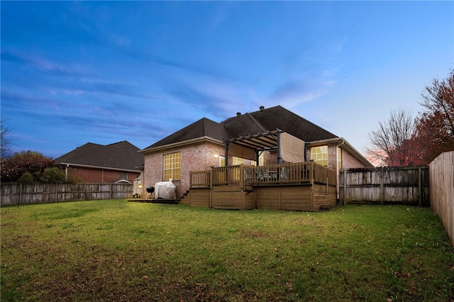 back house at dusk with a pergola, a deck, and a yard