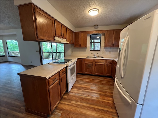 kitchen featuring a textured ceiling, white appliances, dark wood-type flooring, and backsplash