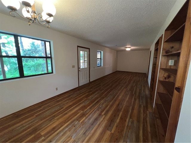 interior space featuring dark hardwood / wood-style flooring, a textured ceiling, and a notable chandelier