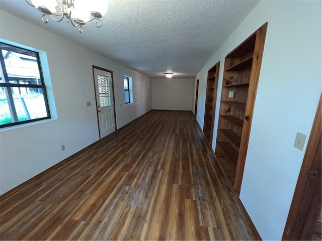 entrance foyer featuring a textured ceiling, a notable chandelier, and dark wood-type flooring