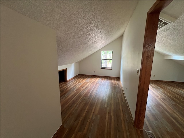 bonus room featuring dark hardwood / wood-style flooring, lofted ceiling, and a textured ceiling