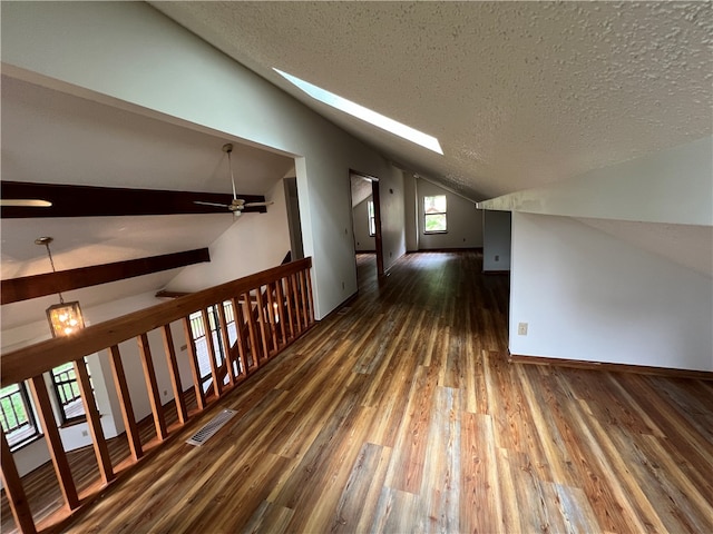 hall featuring dark hardwood / wood-style floors, lofted ceiling with skylight, and a textured ceiling