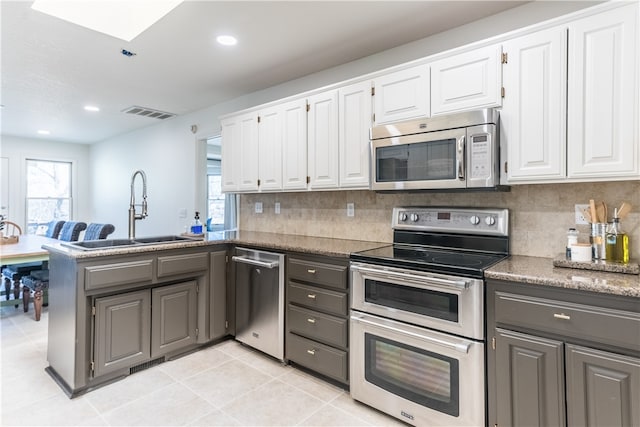 kitchen with white cabinets, backsplash, stainless steel appliances, and sink