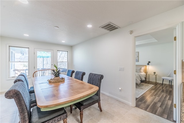 dining space with a textured ceiling and light hardwood / wood-style flooring