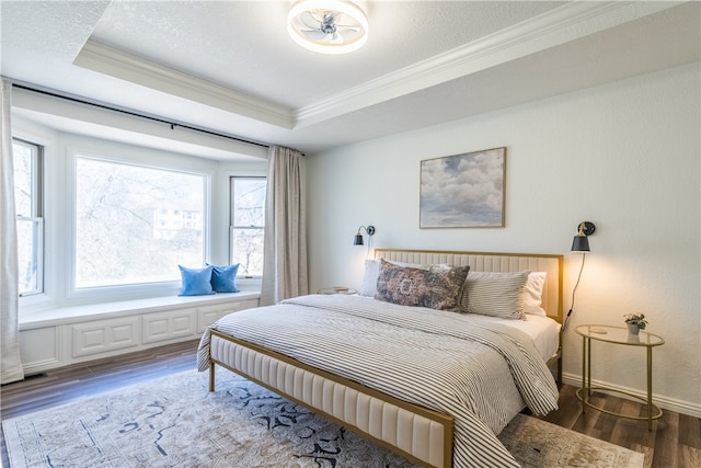 bedroom featuring hardwood / wood-style flooring, a textured ceiling, crown molding, and a tray ceiling