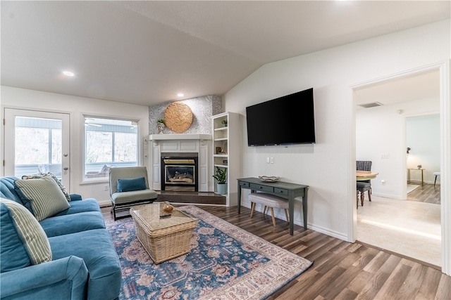 living room featuring a large fireplace, hardwood / wood-style flooring, and vaulted ceiling