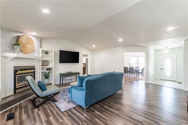 living room with a textured ceiling, dark wood-type flooring, and vaulted ceiling