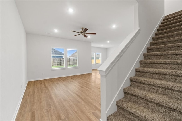 staircase with wood-type flooring and ceiling fan