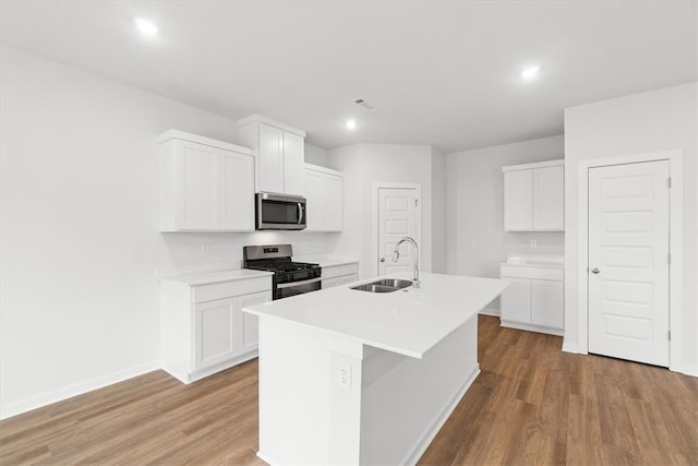 kitchen featuring sink, light hardwood / wood-style flooring, an island with sink, white cabinetry, and stainless steel appliances