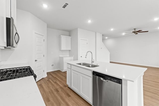 kitchen with a center island with sink, sink, light hardwood / wood-style flooring, appliances with stainless steel finishes, and white cabinetry