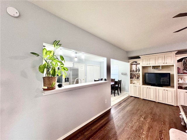 unfurnished living room with dark hardwood / wood-style floors, sink, and vaulted ceiling