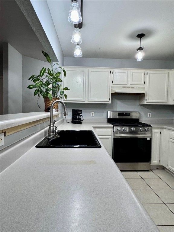 kitchen with pendant lighting, sink, white cabinetry, and stainless steel range oven