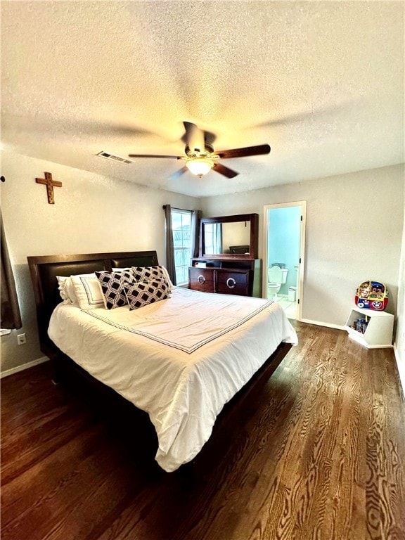 bedroom with ceiling fan, ensuite bathroom, dark wood-type flooring, and a textured ceiling