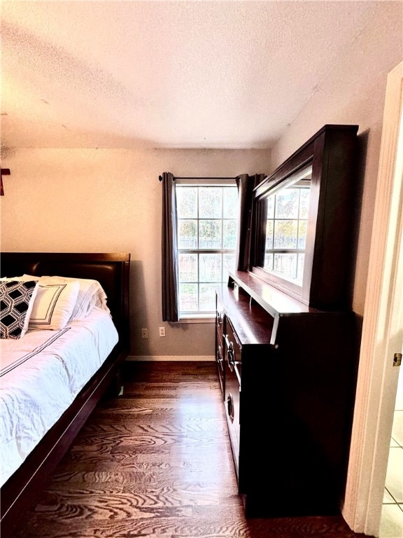 bedroom with a textured ceiling and dark hardwood / wood-style floors