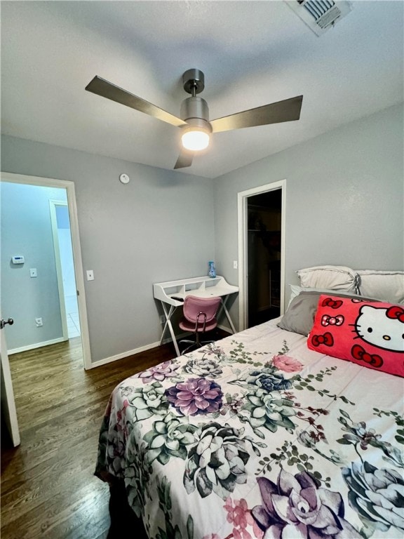 bedroom featuring dark hardwood / wood-style floors, a spacious closet, and ceiling fan