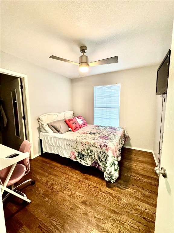 bedroom with a textured ceiling, ceiling fan, and dark wood-type flooring