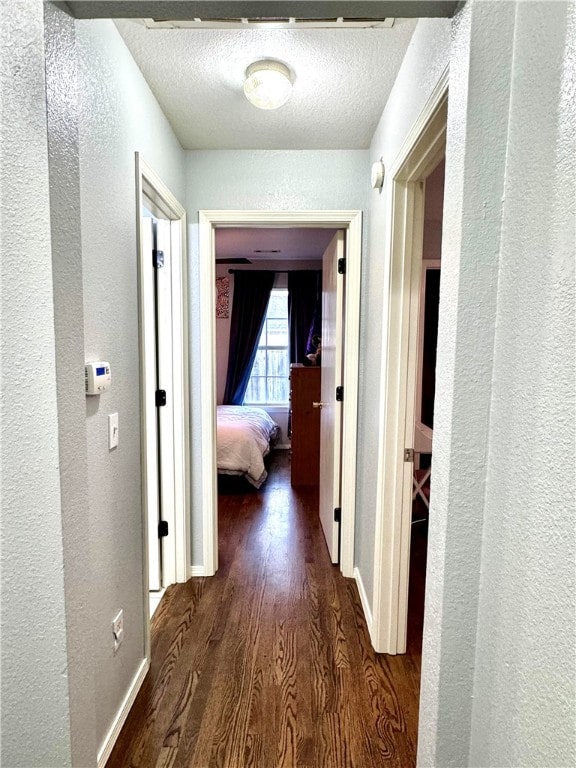 hall featuring a textured ceiling and dark wood-type flooring