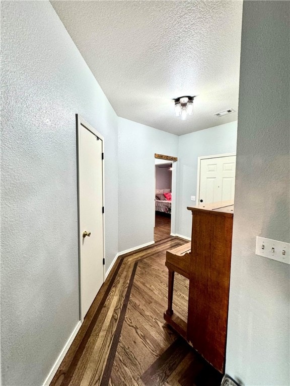 hall featuring wood-type flooring and a textured ceiling