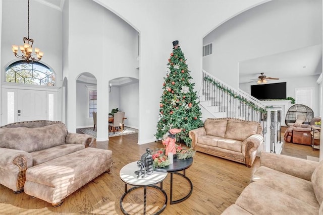 living room with hardwood / wood-style flooring, ceiling fan with notable chandelier, and a high ceiling