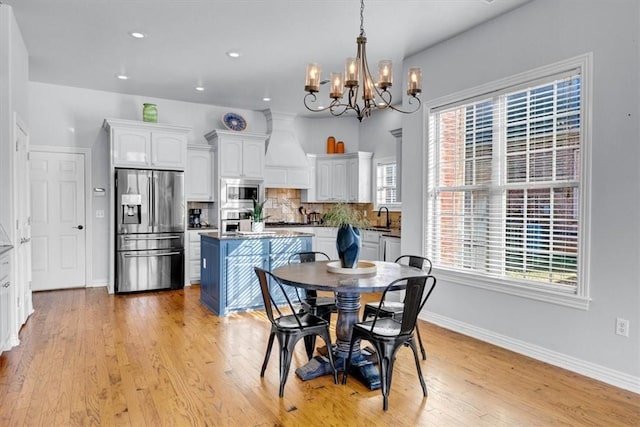 dining room with a notable chandelier, sink, and light wood-type flooring