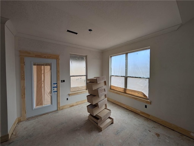 interior space with a textured ceiling, ornamental molding, and baseboards