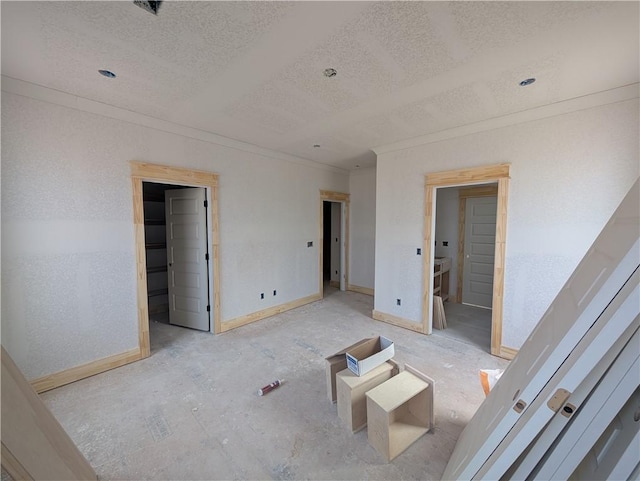 interior space featuring crown molding, baseboards, a walk in closet, and a textured ceiling