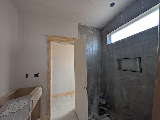 full bath featuring tile patterned flooring, tiled shower, and a textured ceiling