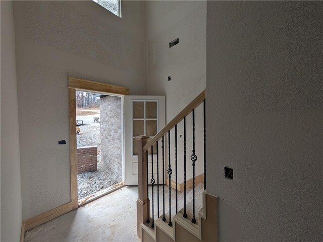 entrance foyer with visible vents, a textured wall, a high ceiling, and stairs