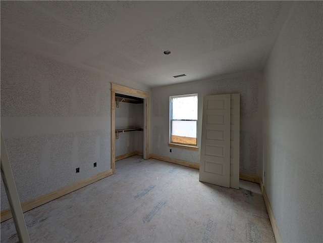 unfurnished bedroom featuring a textured ceiling, a closet, visible vents, and baseboards