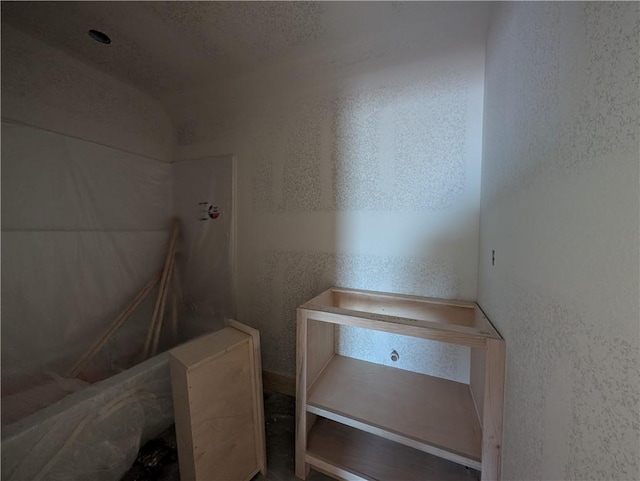 bathroom featuring a textured wall and a shower