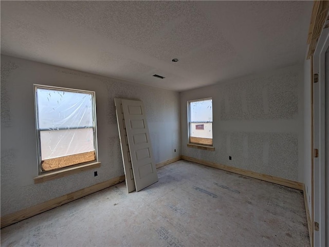 unfurnished bedroom featuring visible vents, a textured ceiling, and baseboards