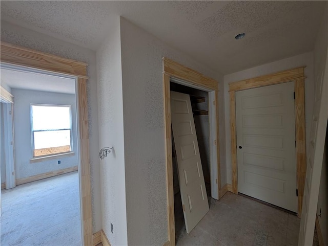 hallway featuring a textured wall and a textured ceiling