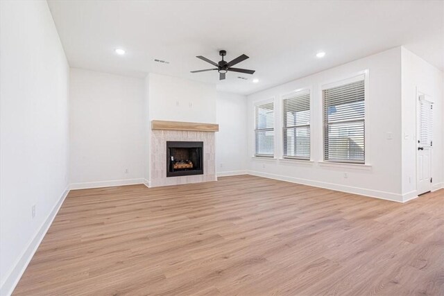 unfurnished living room featuring ceiling fan, a premium fireplace, and light hardwood / wood-style flooring