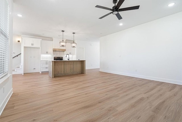 unfurnished living room featuring light hardwood / wood-style floors, ceiling fan, and sink