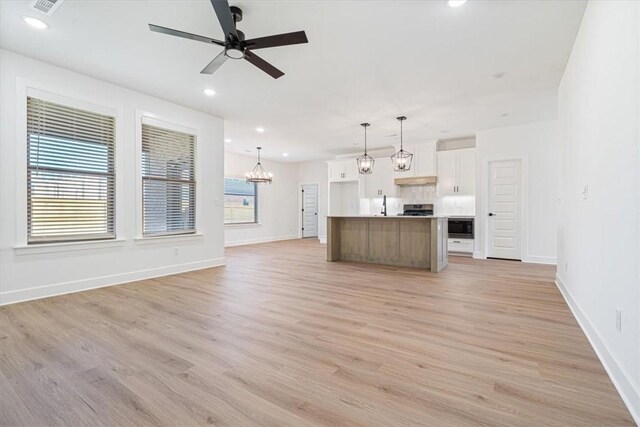 unfurnished living room with a healthy amount of sunlight, ceiling fan, and light wood-type flooring