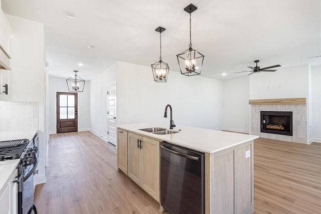 kitchen featuring a kitchen island with sink, stainless steel range with gas cooktop, a fireplace, sink, and black dishwasher