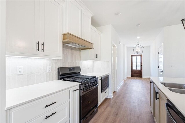 kitchen with white cabinets, dishwasher, light hardwood / wood-style floors, premium range hood, and gas stove