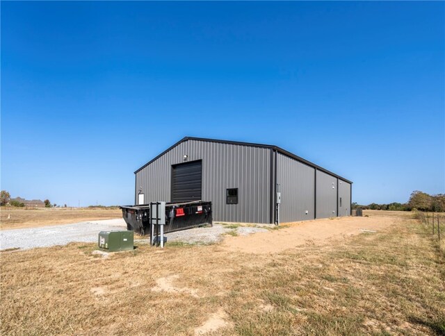 view of outdoor structure featuring a yard, a rural view, and a garage