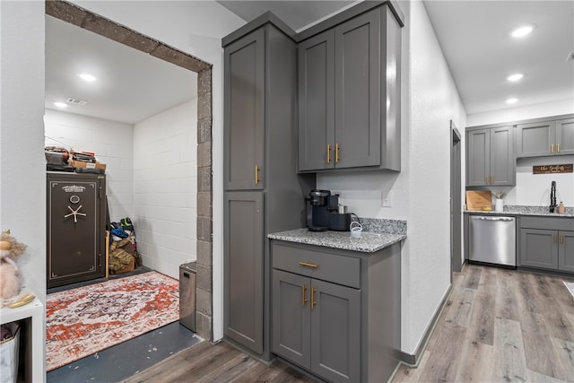 kitchen featuring gray cabinetry, dishwasher, sink, light stone counters, and light hardwood / wood-style floors